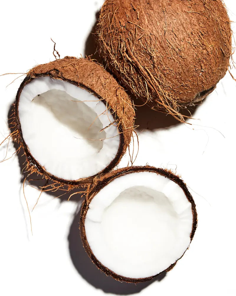 one full coconut and one coconut split in half, laying against a white background