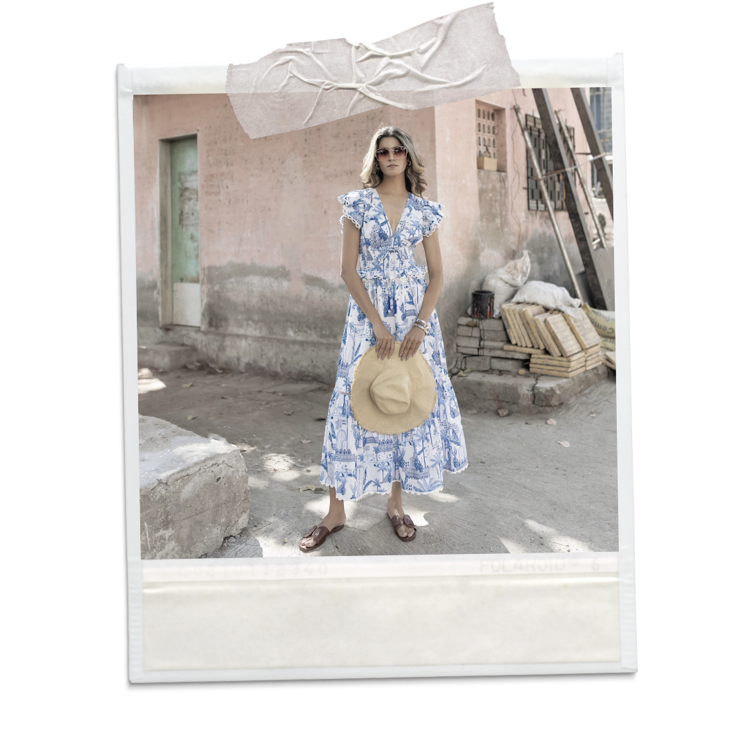 A polaroid picture of a blonde woman wearing a long, white and blue printed dress.