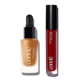 A dropper bottle with a black cap containing liquid bronzer and a red lip gloss with black cap, photographed from a birds' eye view against a white background